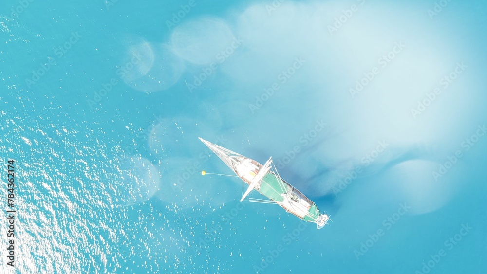 Naklejka premium Bird's eye view of a sailing ship on the light blue water surface.