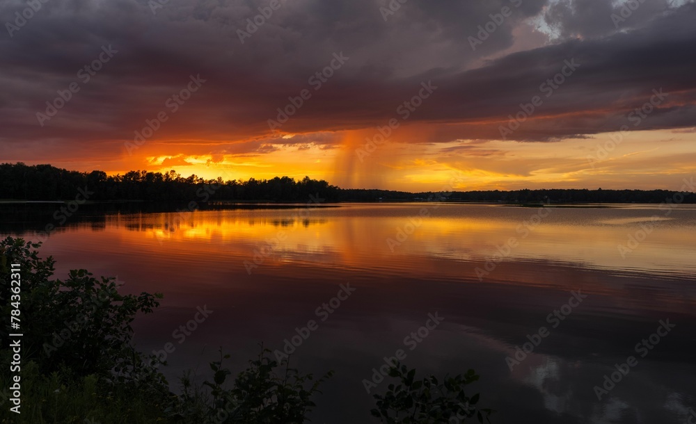 Beautiful view of a lake under the cloudy sky during orange sunset