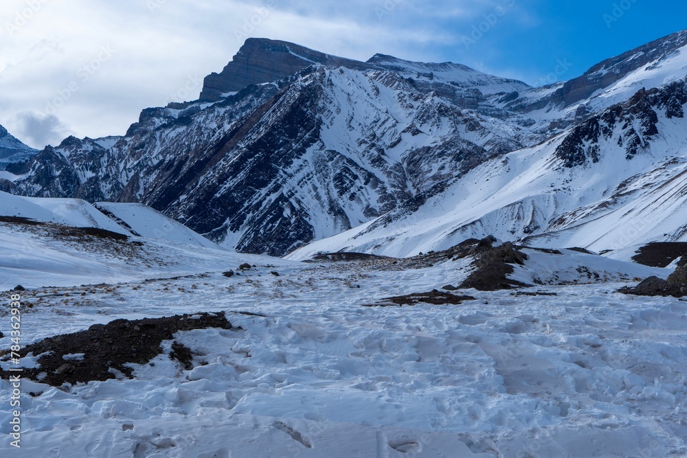 Fototapeta premium Image of mountains covered by snow under the cloudy blue sky.