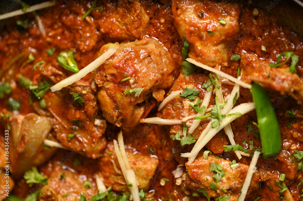 Spicy red boneless chicken handi topped with ginger closeup Spicy red boneless chicken handi topped with ginger closeup