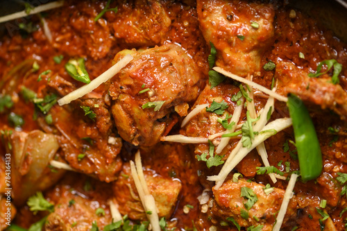 Spicy red boneless chicken handi topped with ginger closeup