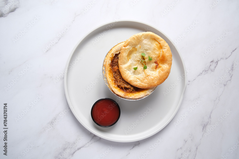 Small open meat pie with side of tomato sauce Small open meat pie with side of tomato sauce