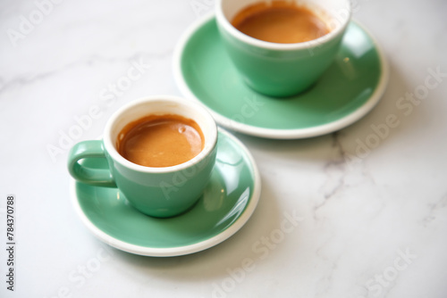 Pair of espressos in teal cup on marble table photo