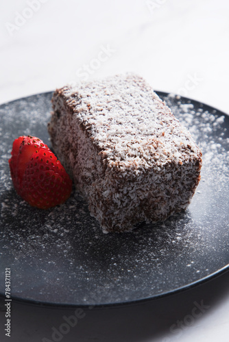 Lamington with sliced strawberry on plate photo