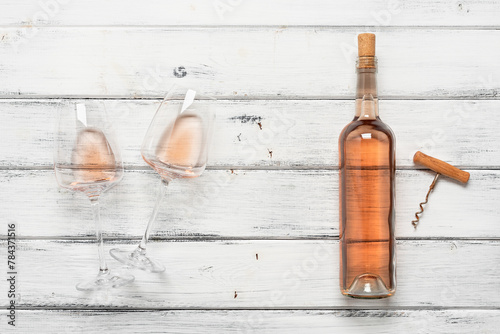 Rose wine in a bottle, in a glass and a corkscrew on a white wooden table. Top view, flat lay. Wine tasting concept. Pink wine.