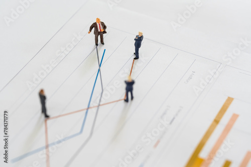 A group of miniature businessman looking at line chart, review on volatility stock market line graph data report