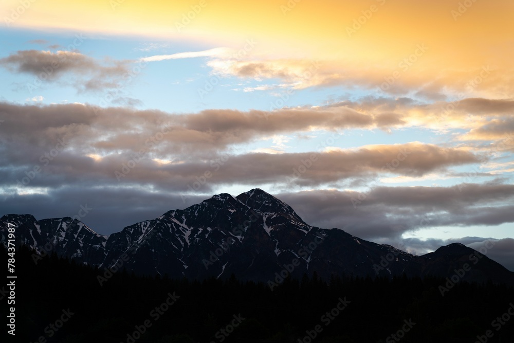 Big mountains with snowy peaks against the cloudy sunset sky