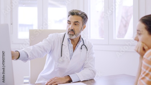 Doctor pointing to computer giving an explanation to a patient