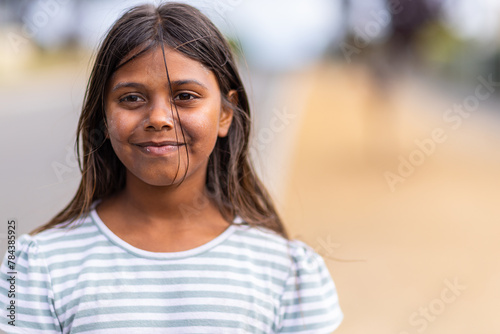 aboriginal girl with stray hair on face and blurry background photo