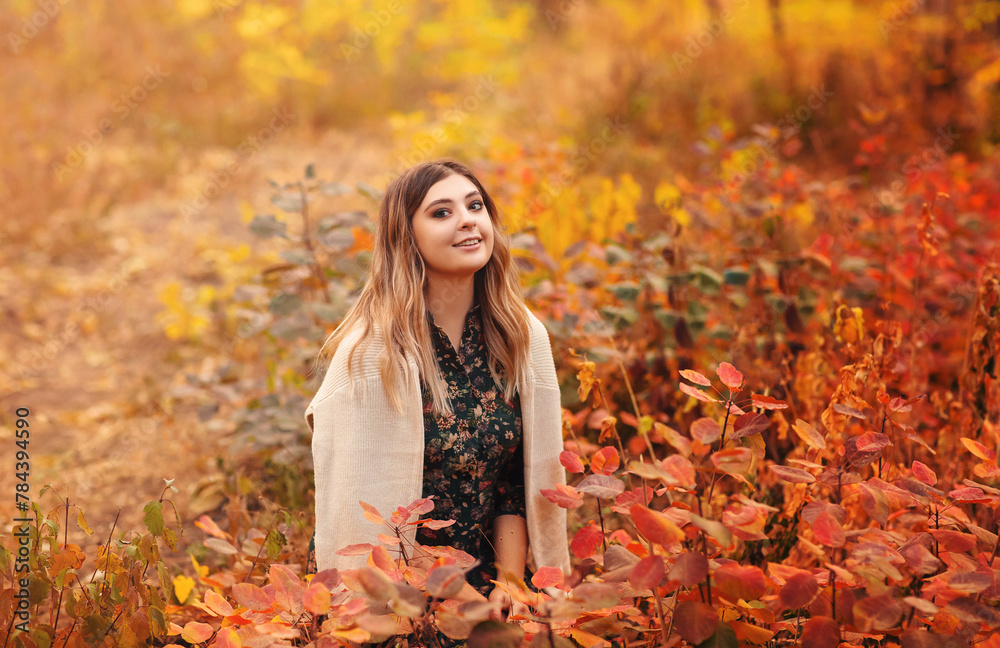 Beautiful young blonde woman in dress sitting with pensive look in tall grass in autumn forest Beautiful young blonde woman in dress sitting with pensive look in tall grass in autumn forest