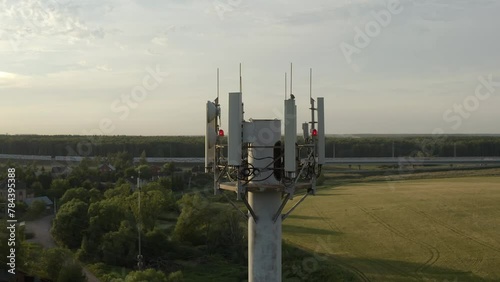 Drone flying around cell tower antennas, base station transmitting 5g, 4g signals in countryside.