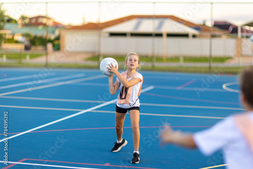 ten year old girl ready to throw netball to teammate at training photo