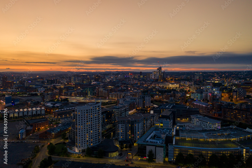 Aerial night time photo taken at sunset of the area in Leeds known as The Leeds Dock showing the whole of the West Yorkshire city with the sun setting in the background