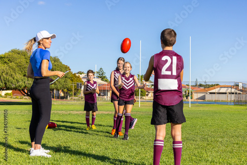 woman wearing activewear supervising kids football training photo