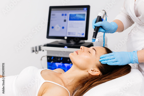 Close-up of a cosmetologist's hands polishing and cleansing the skin of a middle-aged woman's face using a vacuum machine. Concept of skin care, rejuvenation and cosmetology.