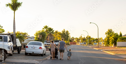 young family walking away along street
