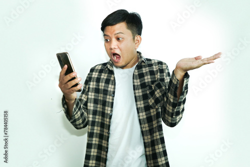 Young Asian man shocking while looking his mobile phone and an open left hand photo