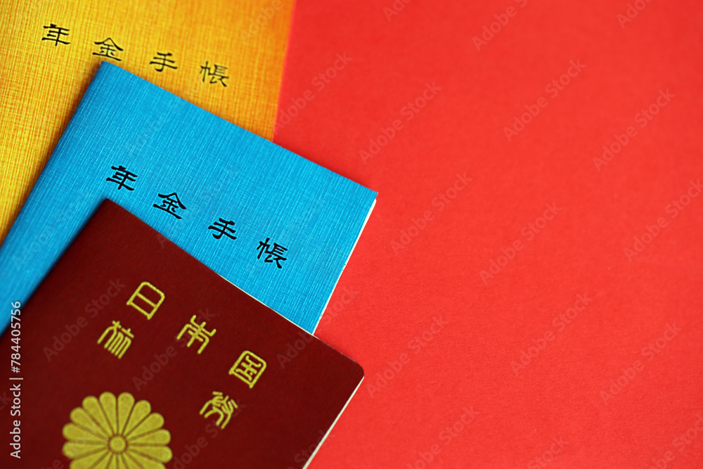 Japanese pension insurance booklets on table with passport. Blue and orange pension book for japan pensioners close up Japanese pension insurance booklets on table with passport. Blue and orange pension book for japan pensioners close up