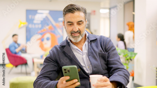 Mature employee using phone in modern coworking