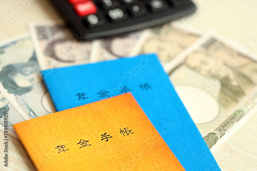 Japanese pension insurance booklets on table with yen money bills and calculator on table close up