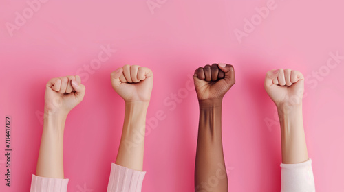 Women's Day, a female raised fist isolated on a pink background. 