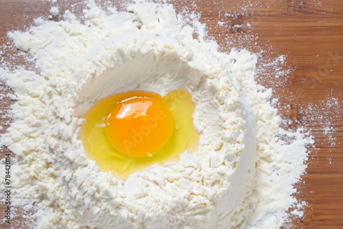 preparing the dough. there is scattered flour with a broken chicken egg on the table, close-up top view, cooking concept
