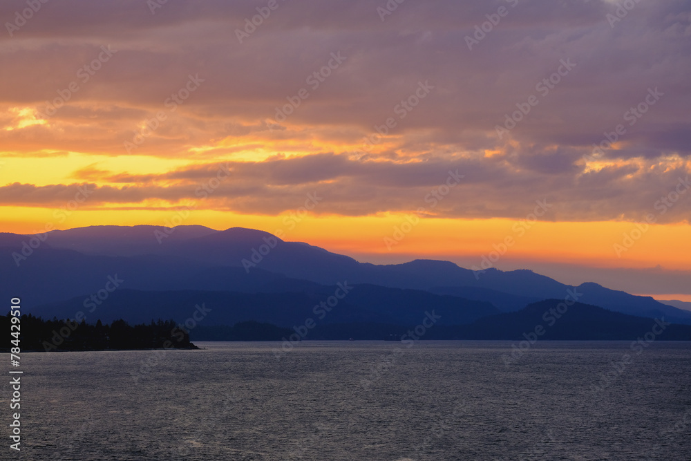 Panoramic sunrise or sunset landscape nature coastal scenery with beautiful fire sky and dramatic cloudscapes in Alaska Inside Passage glacier mountain range view