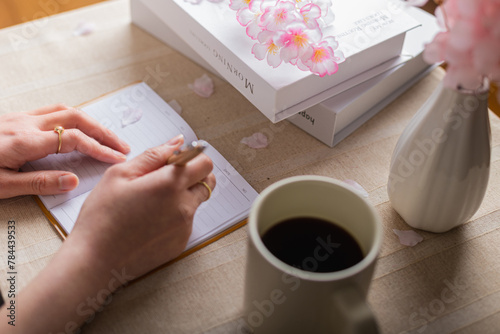 日本の春に桜の木の下でノートにメモをする女性の手元