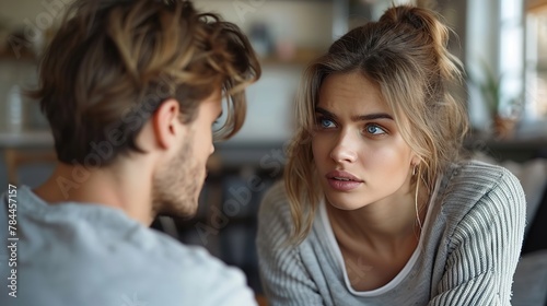Emotionally stressed young couple arguing at home. Portrait of an angry irritated man and woman talking and looking at each other with annoyance. Relationship problems, family conflicts