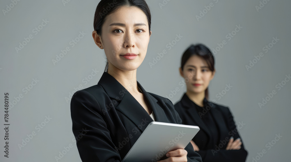 Asian businesswoman in black suits holding smart tablet pad isolated on gray background. Concept of business, finance, professional, profession, occupation, employee boss employer. Copy space for text Asian businesswoman in black suits holding smart tablet pad isolated on gray background. Concept of business, finance, professional, profession, occupation, employee boss employer. Copy space for text