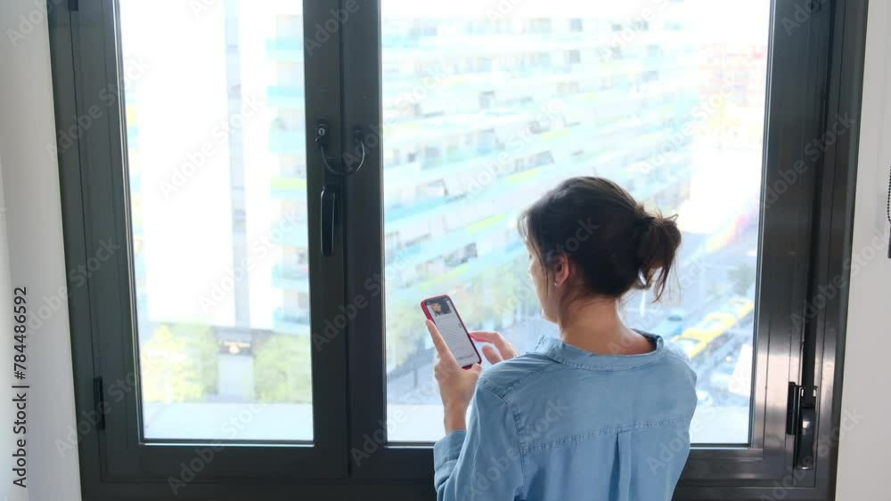 Woman With Her Back In Front Of A Window In A Big City Typing With