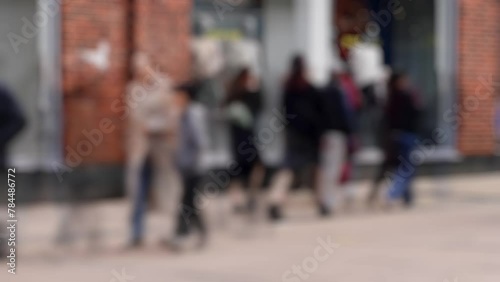 Daytime time-lapse of crowds of shoppers walking through a pedestrianised section of a British inner-city shopping street. 