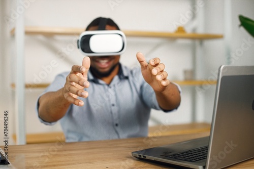 Black male entrepreneur sitting in office and using virtual reality glasses