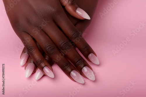 Elegant almond-shaped glitter manicure on dark skin against a pink background, perfect for beauty concepts