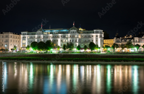Salzburg, Austria, August 15, 2022. Iconic night image of the luxury hotel Sacher, reflected in the waters of the Salzach river. Copy space.
