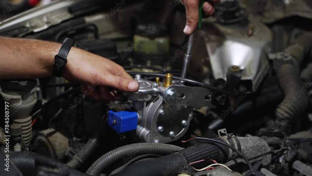 Auto mechanic installs LPG reducer vaporizer in car engine. Hands fix low pressure regulator for gas conversion. Sequential multipoint LPG injection setup. Automotive maintenance, fuel system upgrade. Auto mechanic installs LPG reducer vaporizer in car engine. Hands fix low pressure regulator for gas conversion. Sequential multipoint LPG injection setup. Automotive maintenance, fuel system upgrade.