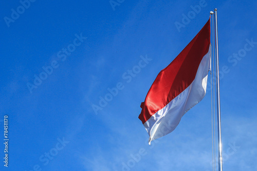 The Indonesian flag flutters againts the background of bright blue sky.. Independence day concept