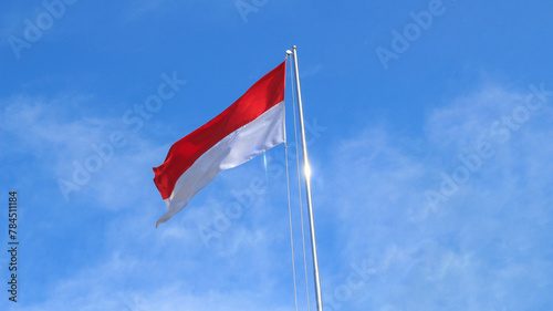The Indonesian flag flutters againts the background of bright blue sky.. Independence day concept