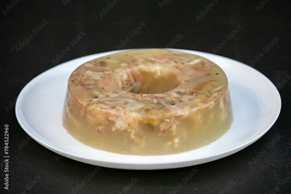 Traditional Ukrainian festive cold appetizer. Pork jelly with pieces of meat with parsley isolated on a white background. Drehlhi