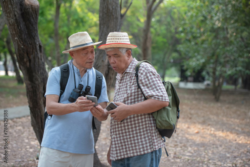 Asian tourists use their mobile phones to search for information about landmarks. Rest happily in retirement.