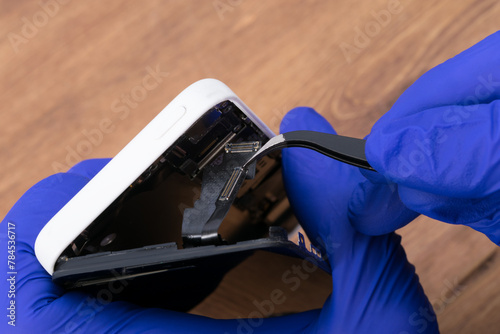 hands of a smartphone repairman opening the phone to identify the problem and replace the faulty part, close-up