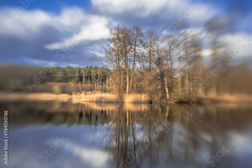 Landscape by a small lake in a forest in podlasie on a sunny,spring day with a blurred background. © Zdzislaw