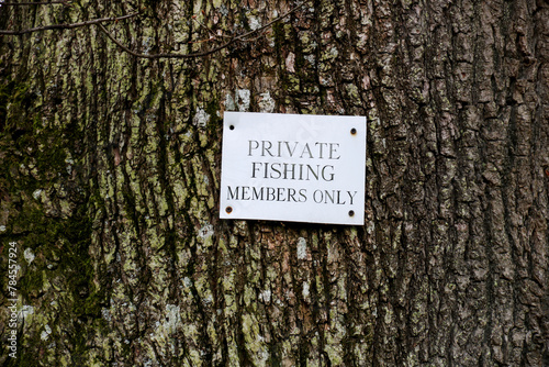 Private Fishing Sign Attached to a Tree Trunk in a Rural Location