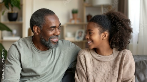 African American father and daughter smiling at each other, family bonding, neutral tones. Copy space.