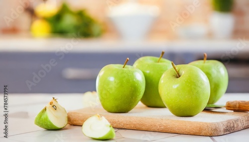 A selection of fresh fruit: green apple, sitting on a chopping board against blurred kitchen background; copy space
