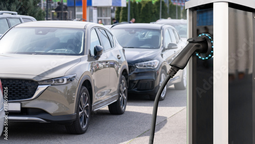Electric vehicles charging station on a background of a row of cars. Concept © scharfsinn86