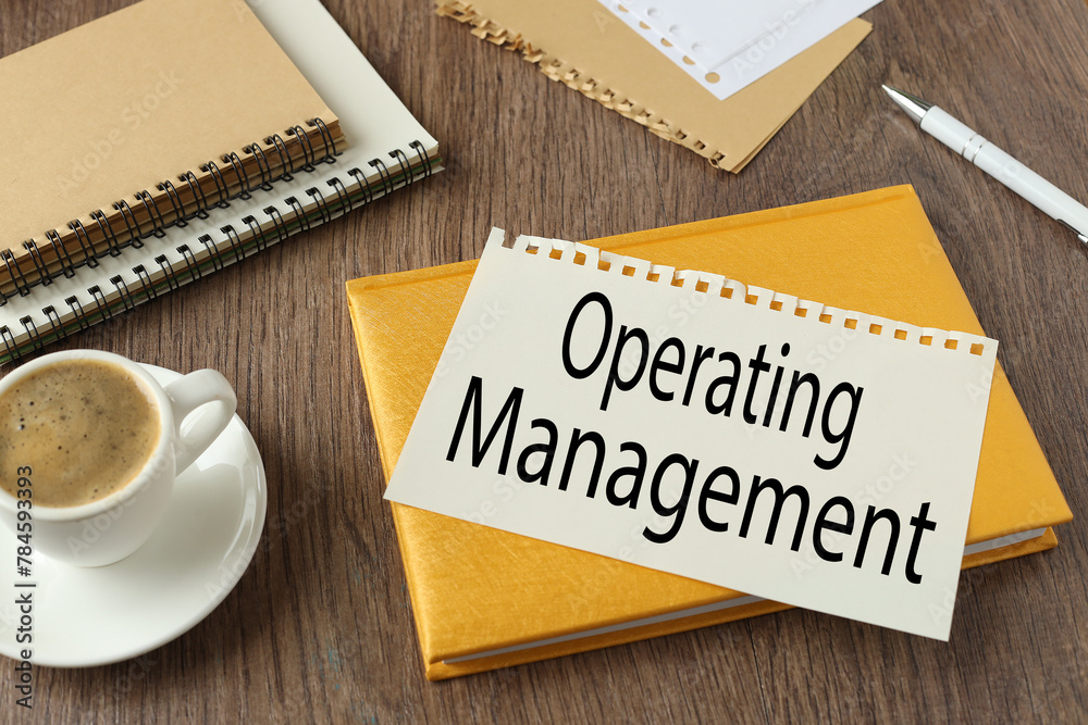 Operating MANAGEMENT cup of coffee and yellow notepad. text on torn page Operating MANAGEMENT cup of coffee and yellow notepad. text on torn page