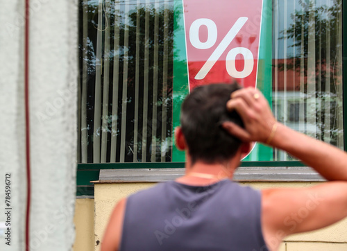 Man scratching head while looking at percentage sign in window display
