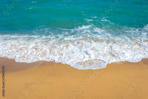 A frothy blue ocean wave on a clean sandy sea beach.