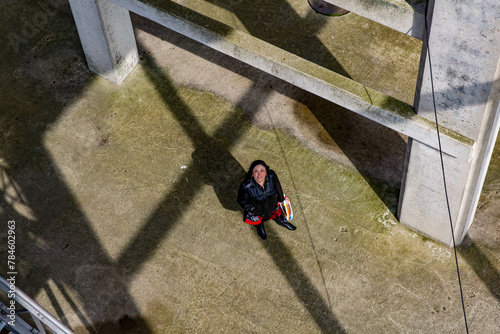 Aerial view of a middle aged woman standing and looking up, concrete floor with moss, pillars in construction of an old mine, sunny day in Belgium